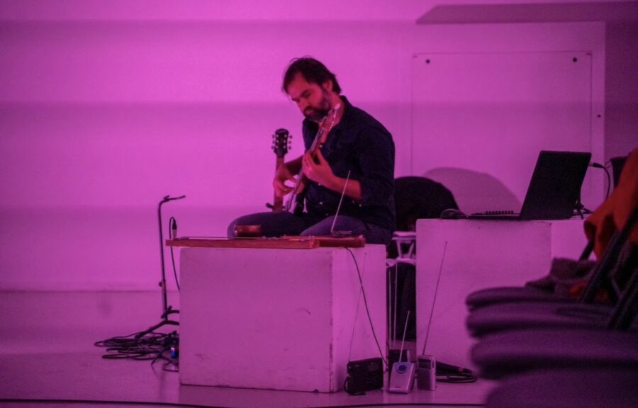 Musicien et auteur jouant de la guitare sous lumière rose